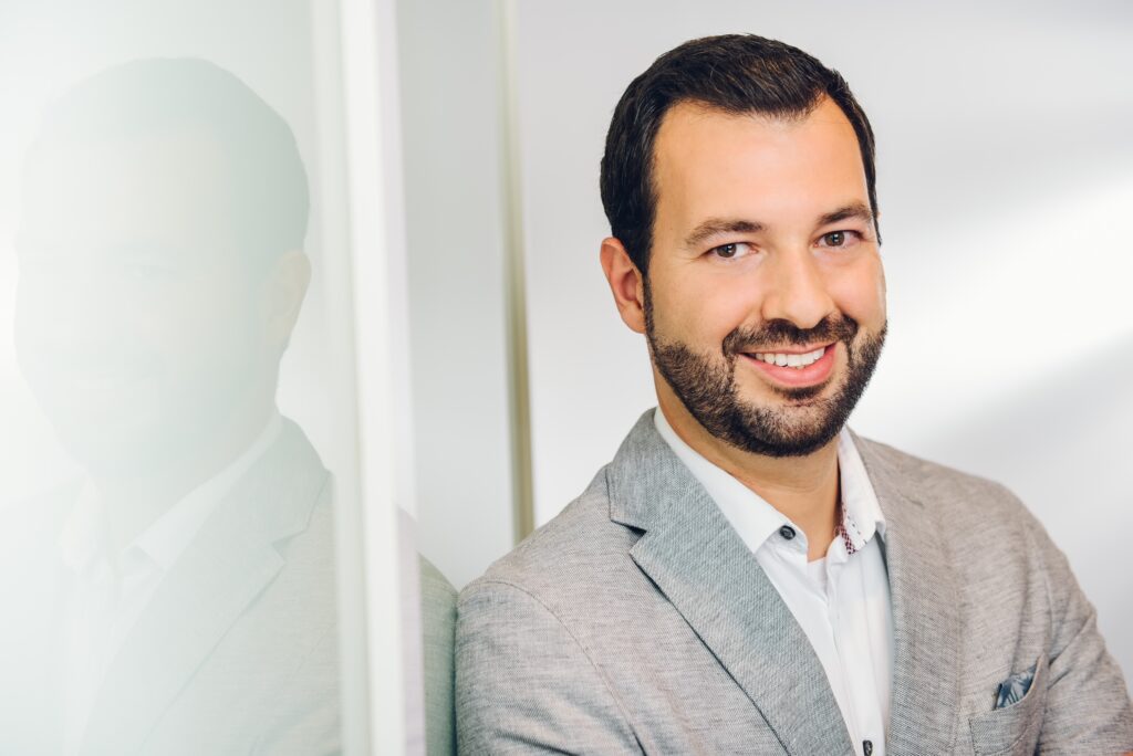 Ein freundlicher Immobilienberater bietet persönliche Betreuung und Finanzierungslösungen an, während er lächelnd Immobilienberatung durchführt.